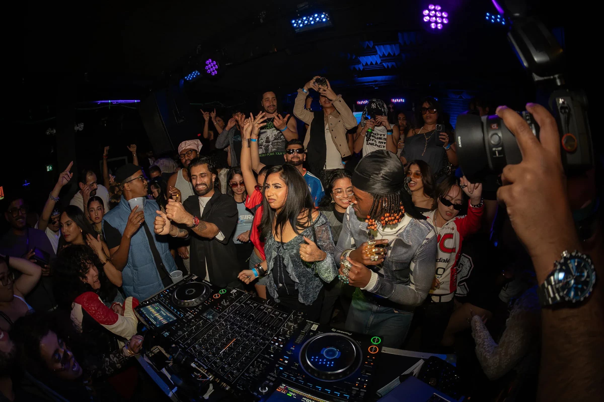 A packed dance floor around the DJ booth at MOOVE Toronto, hands up, stage lights overhead.